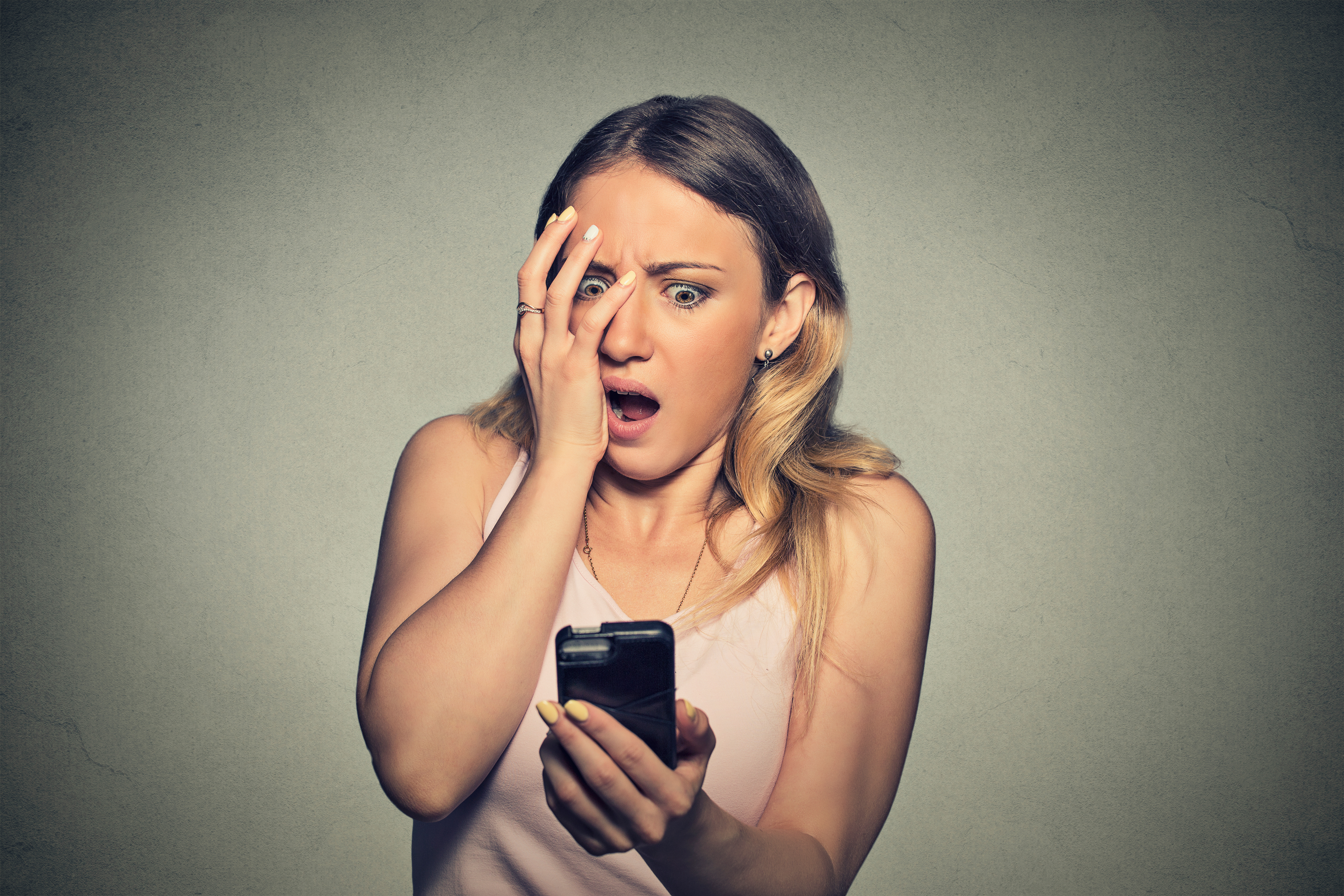 Closeup portrait anxious scared young girl looking at phone seeing bad